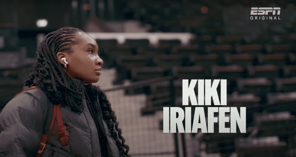 Kiki Iriafen walks onto the basketball court, looking forward. Her name is in bold letters on the screen.